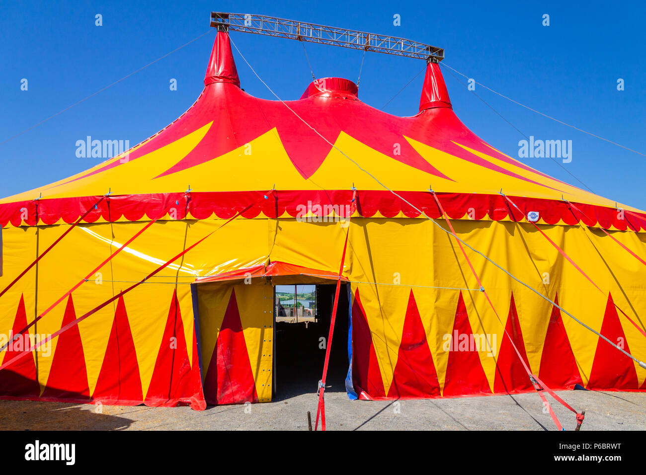 Circus tent or big top with red and yellow design standing out against a clear blue sky. Stock Photo