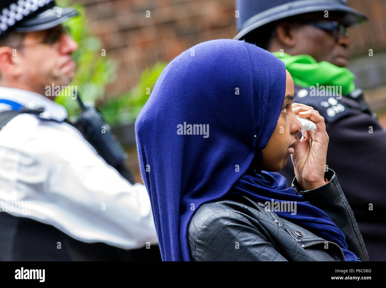 The first anniversary of the 24-storey Grenfell Tower block of public housing flats fire which claimed 72 lives. Young female wipes tears away during the public memorial service, South Kensington, London, UK, 14th June 2018. Stock Photo