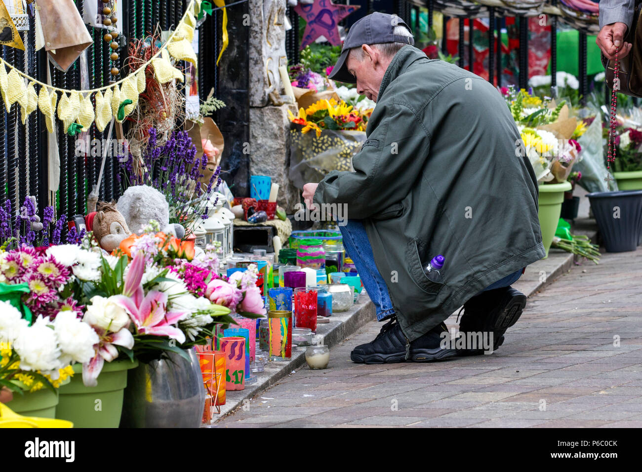 The first anniversary of the 24-storey Grenfell Tower block of public housing flats fire which claimed 72 lives. Man paying his respects at a memorial outside a church near the tower block.  South Kensington, London, UK, 14th June 2018. Stock Photo