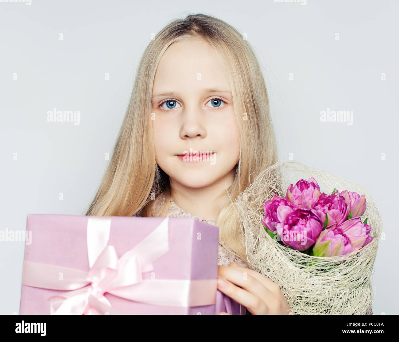 Cute child girl with pink flowers and gift box, portrait Stock Photo