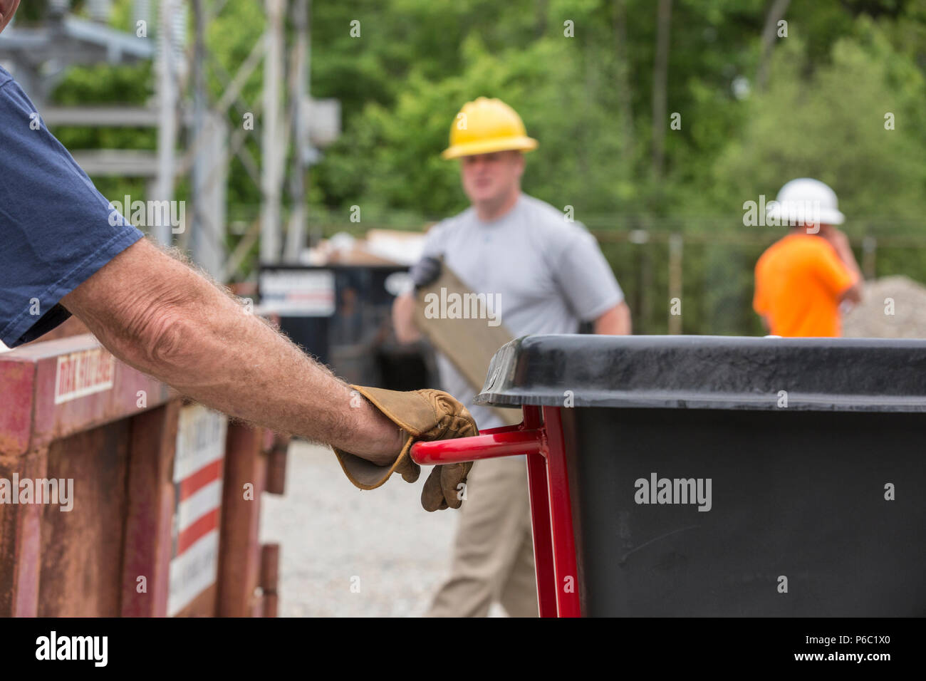 Engineers putting refuse into a dumpster Stock Photo