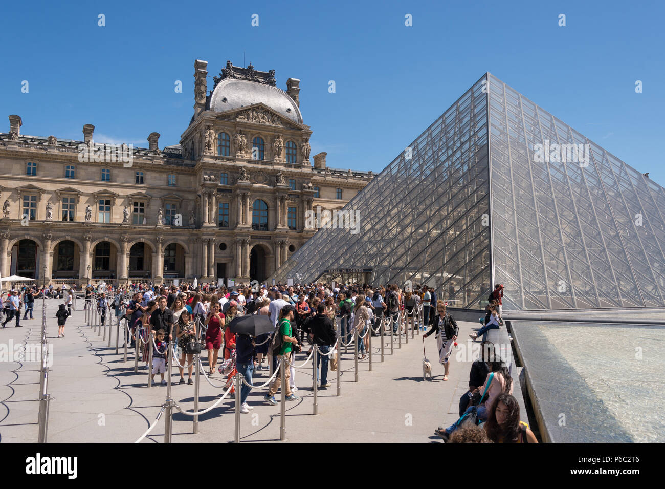 Tourists waiting in line in front of the entrance to the Louvre museum Stock Photo