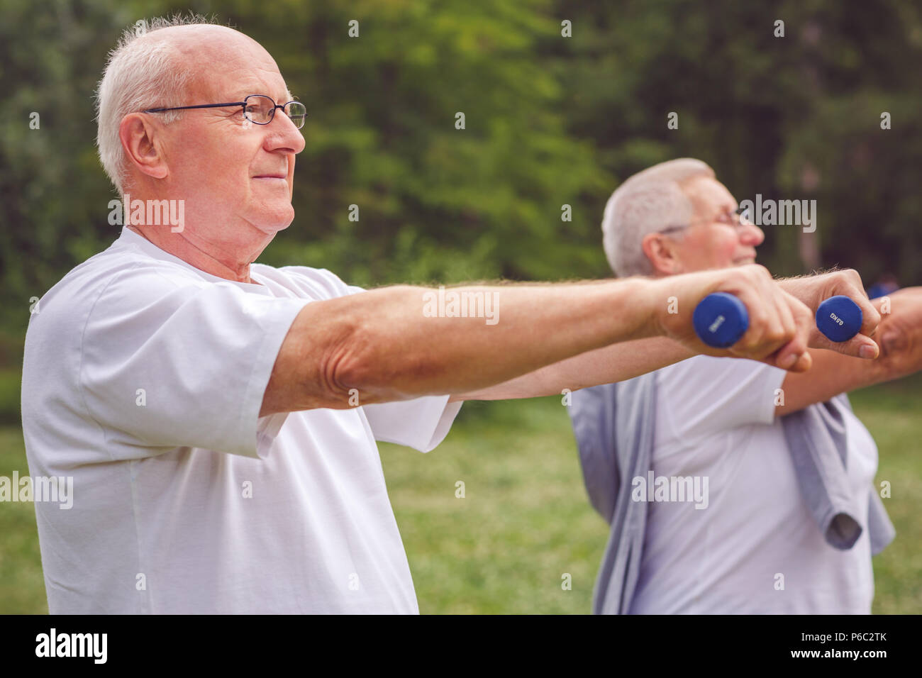 Elderly man exercising with dumbbells in a park Stock Photo