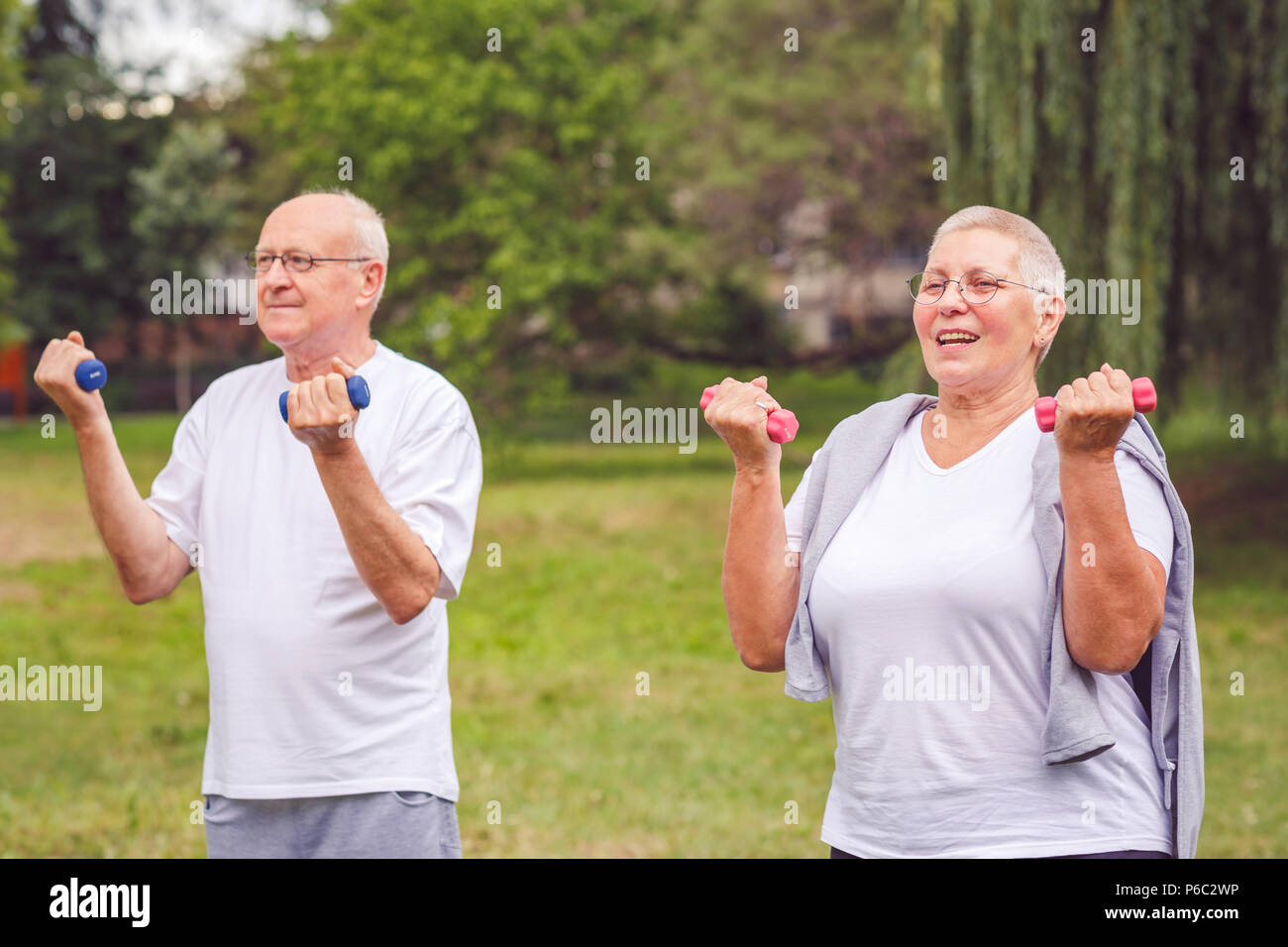 Feeling great in our senior years -Smiling senior man and woman practice with dumbbells in a park Stock Photo