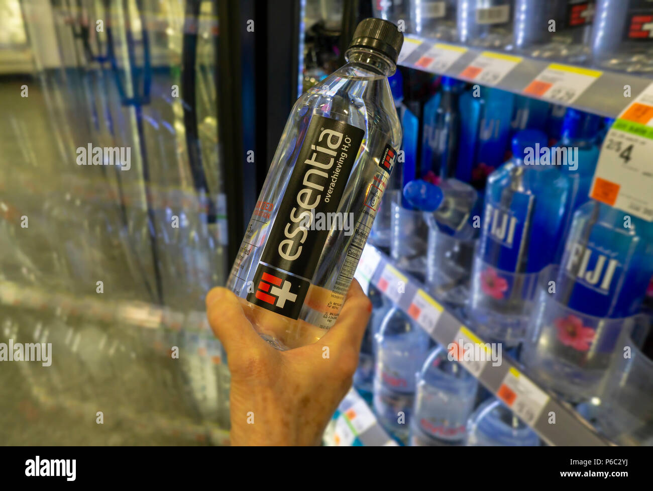Shopper chooses a bottle of Essentia amidst other waters from a cooler in a convenience store in New York on Thursday, June 14, 2018. Essentia, one of players in the functional water space, has hired Credit Suisse to run an auction of the company hoping to attract a larger beverage brand such as PepsiCo or Nestle. Essentia claims superior hydration due to a proprietary method of ionizing the water. (Â© Richard B. Levine) Stock Photo