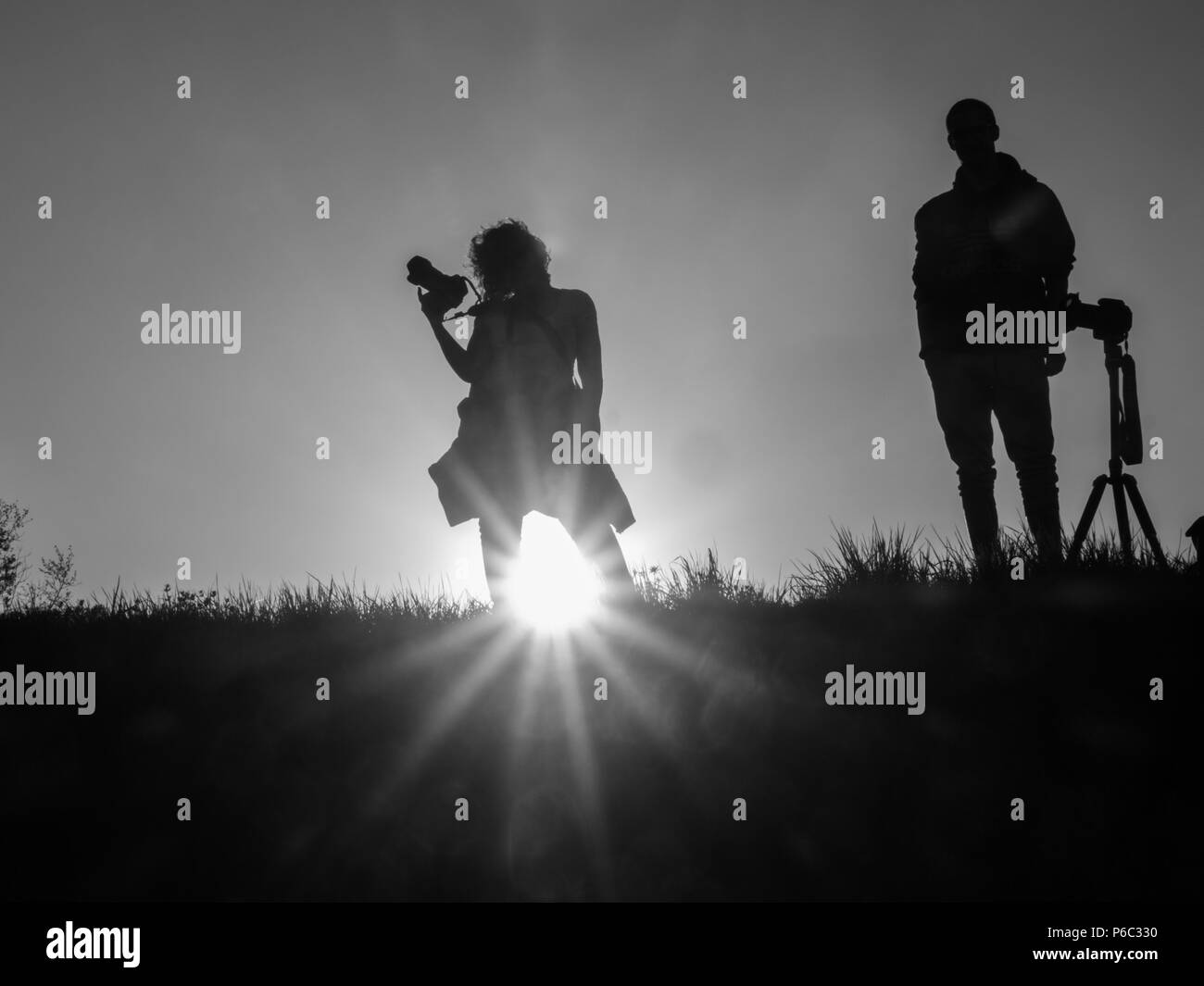 Silhouette of woman and man with photo camera during sunset time. Photographers. Stock Photo