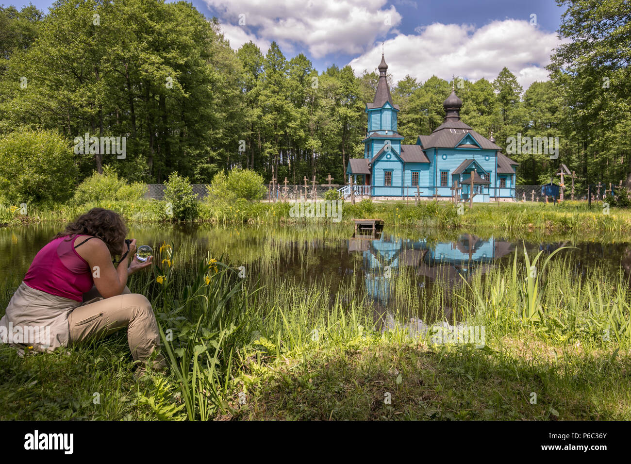 A woman takes picture of  blue, wooden orthodox church.  Podlasie. Podlachia. Poland, Europe. The region is called Podlasko or Podlasze Stock Photo