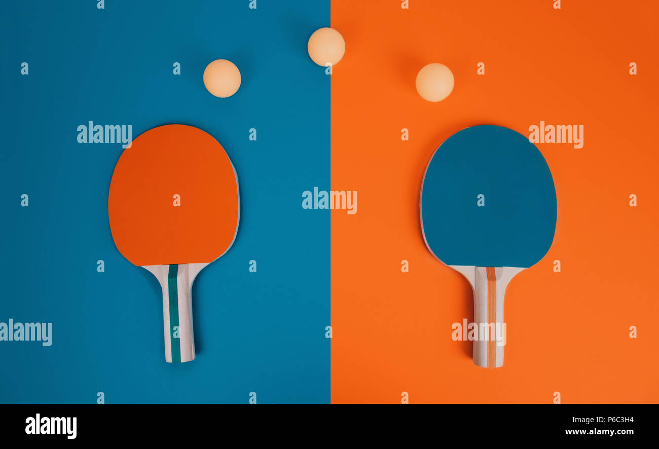 Table tennis or ping pong rackets and balls on an orange and blue table