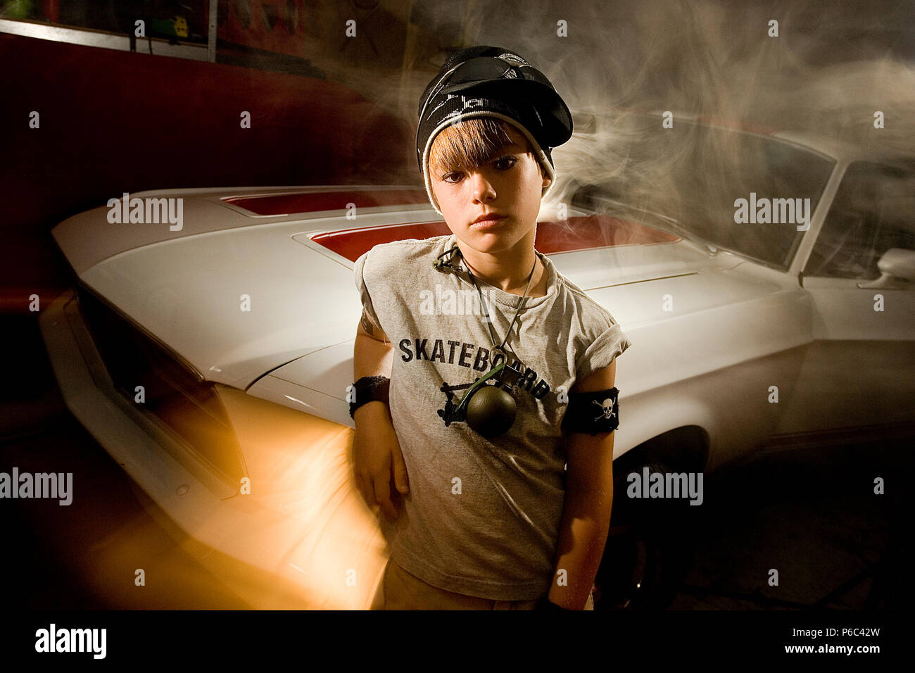 A young boy with a attitude, in a garage after cleaning his fathers muscle car. Stock Photo