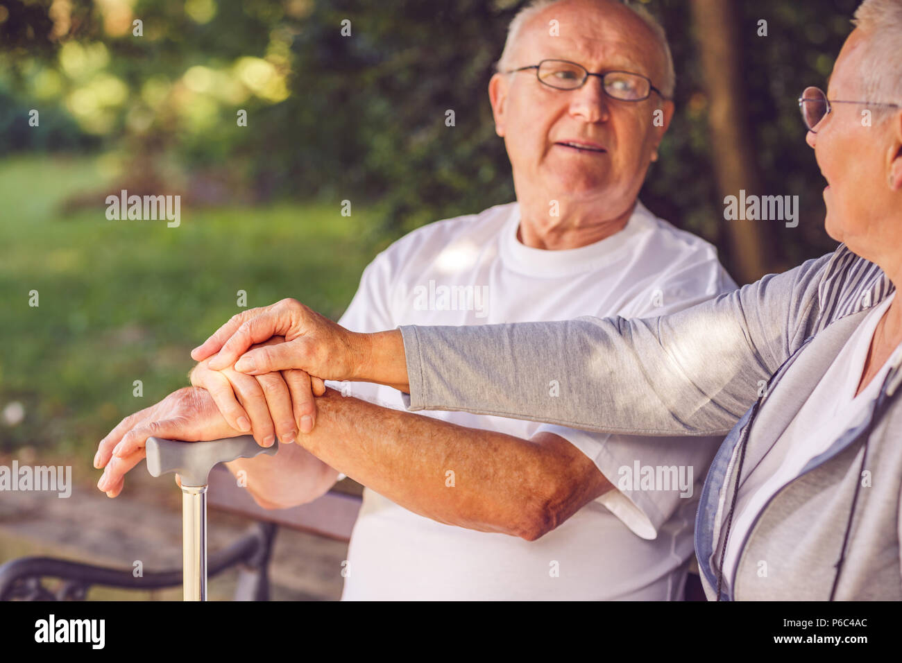 hands of senior couple during walk in park on sunny day Stock Photo