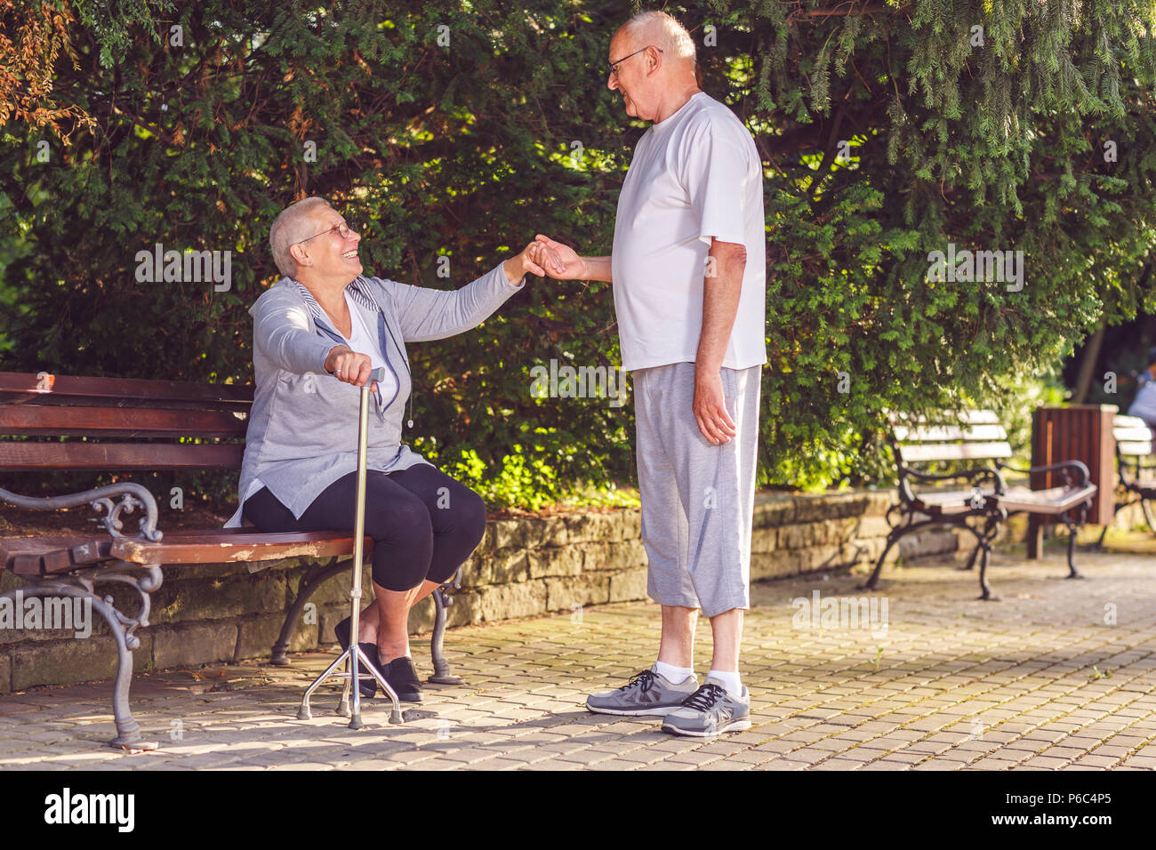 Seniors in park- Smiling elderly man caring wife in the park Stock Photo