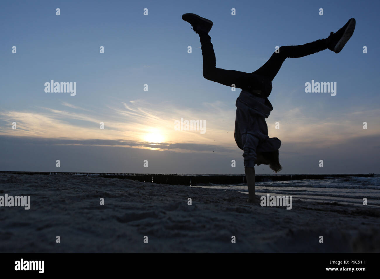Wustrow, Germany - Silhouette, boy makes a handstand on the beach Stock Photo