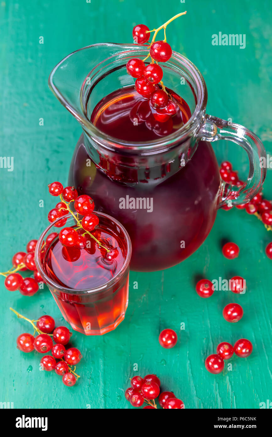 Red currant juice in glass with fruits on wood table. Focus on redcurrant in glass. Stock Photo