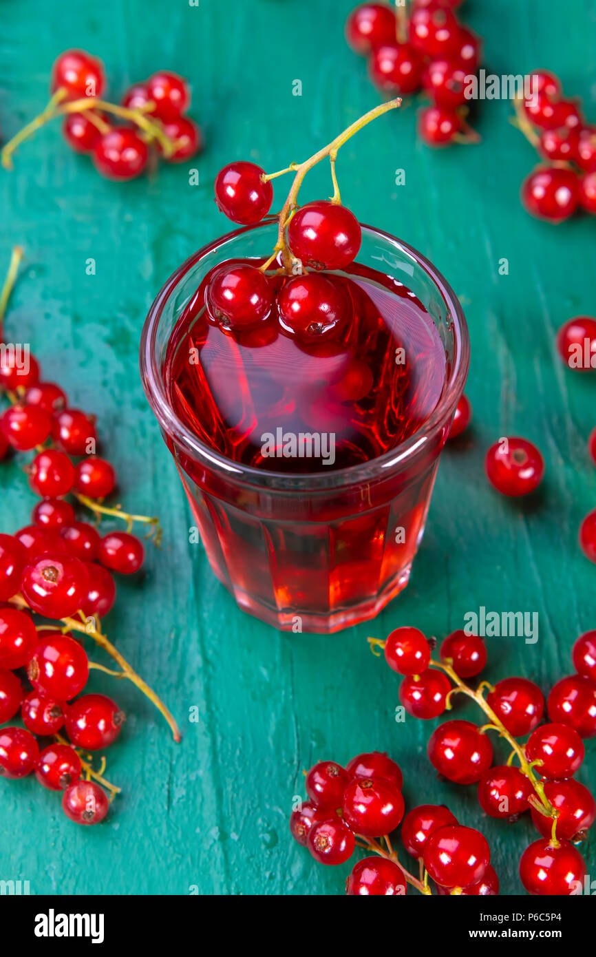 Red currant juice in glass with fruits on wood table. Focus on redcurrant in glass. Stock Photo