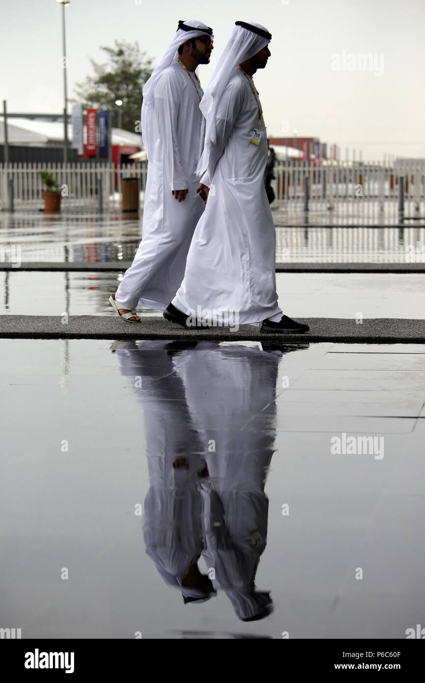 Dubai, men in Arab costume are reflected in a Pfuetze Stock Photo