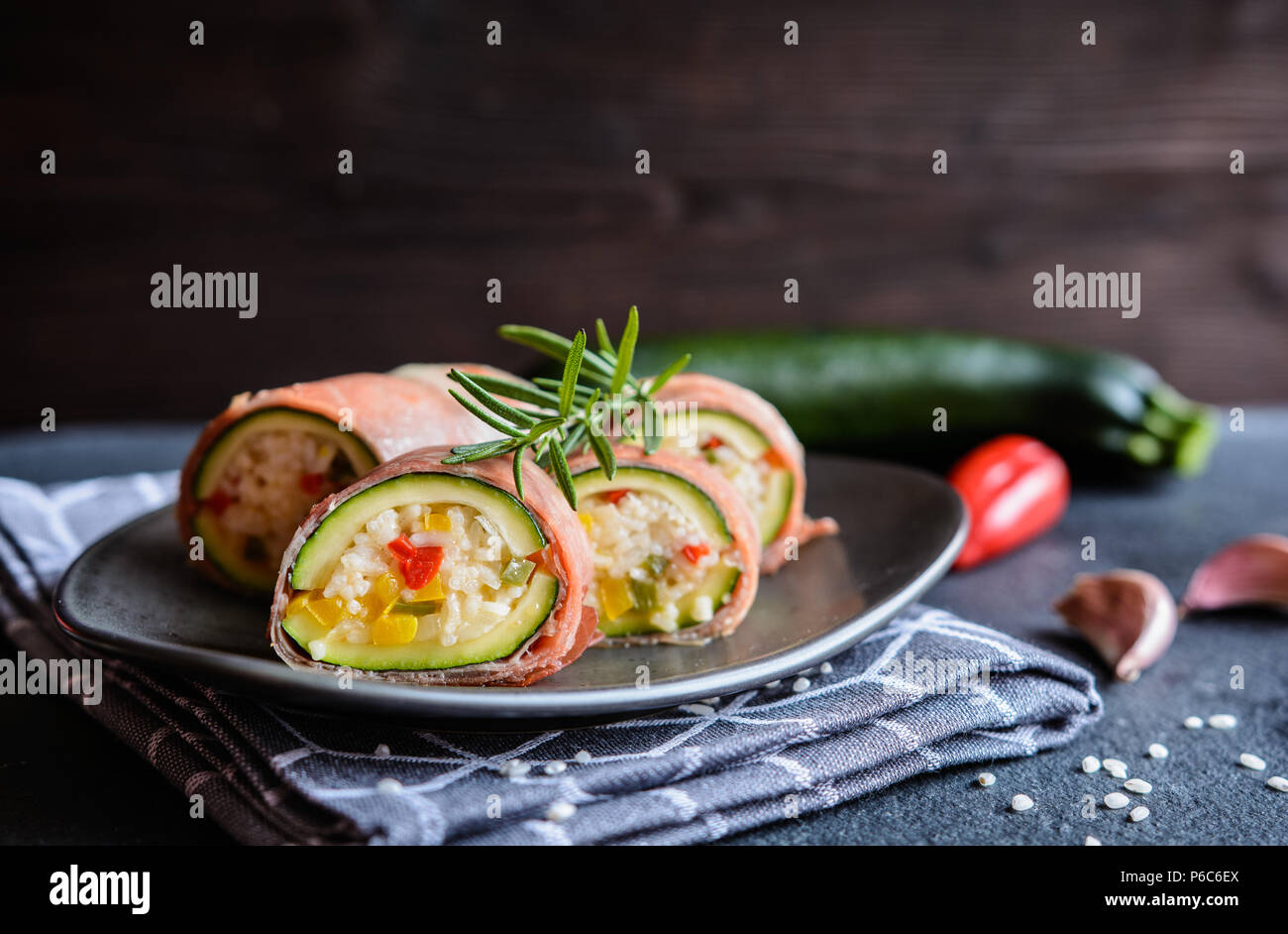 Roasted zucchini stuffed with rice, cheese, pepper and wrapped in Prosciutto slices Stock Photo