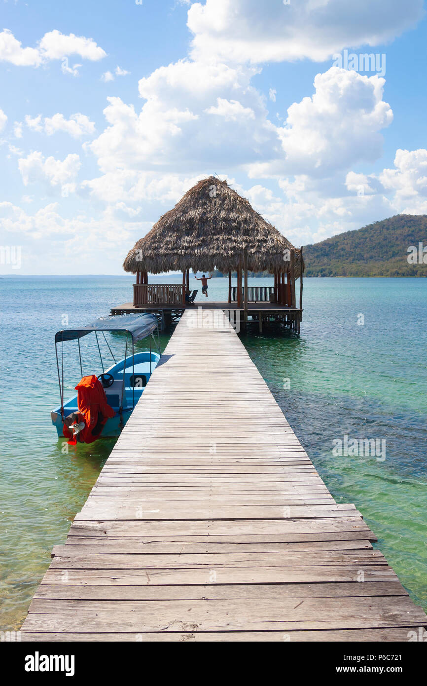 Man jumps off a wooden pier into crystal clear blue lake in Guatemala, North America Stock Photo