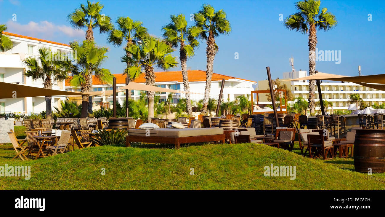 Wooden sun beds, tables and chairs on lawn with green grass for campers