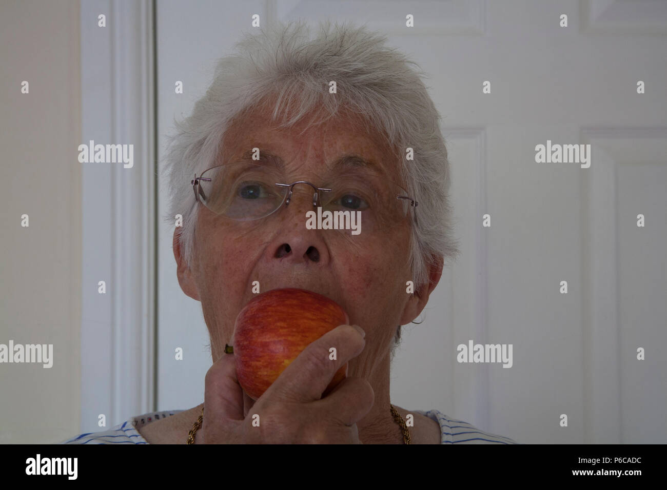 Elderly woman enjoying eating a Royal Gala apple eating one of