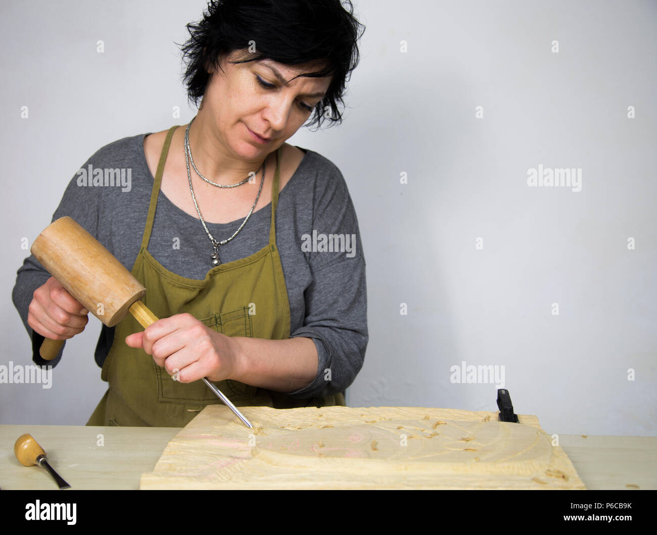 Work Of Woman Artist. Woman sculptor of carver carving wood. Stock Photo