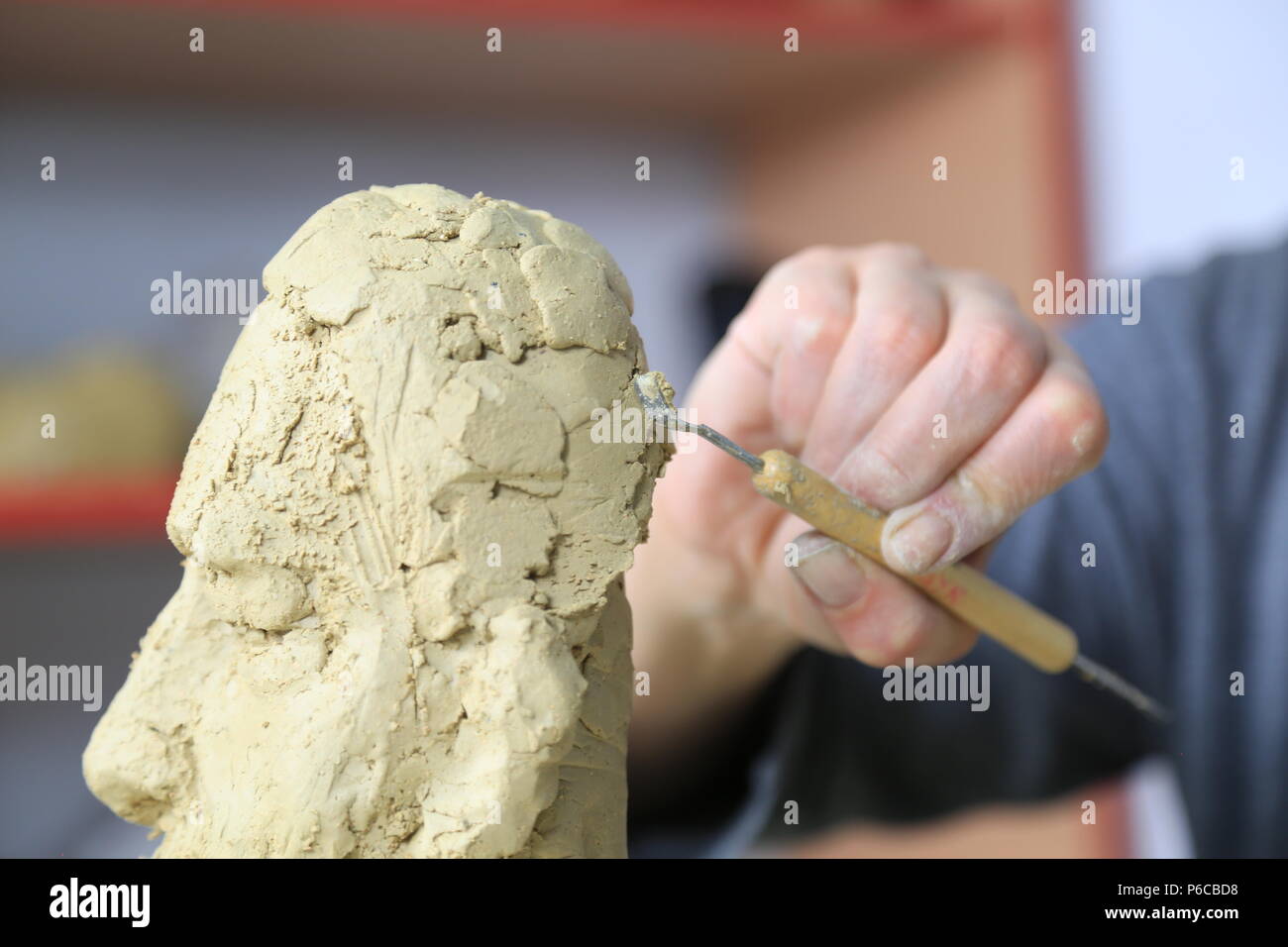 Sculptor artist creating a bust sculpture with clay. She is happy of