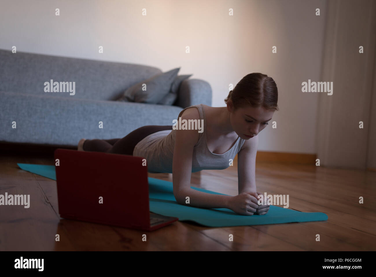 Woman practicing plank pose in living room Stock Photo