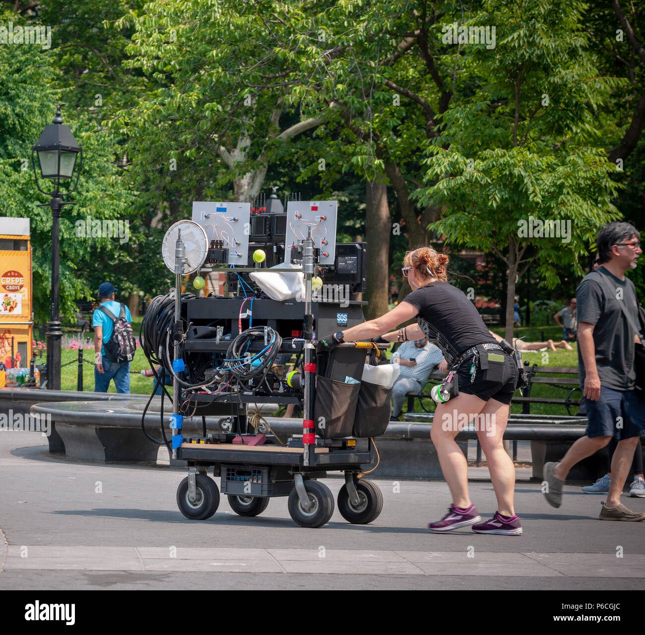 A grip pushes a cart laden with filmmaking equipment for the production of Showtimes' 'Ray Donovan' in Washington Square Park in Greenwich Village in New York on Monday, June 18, 2018. (Â© Richard B. Levine) Stock Photo