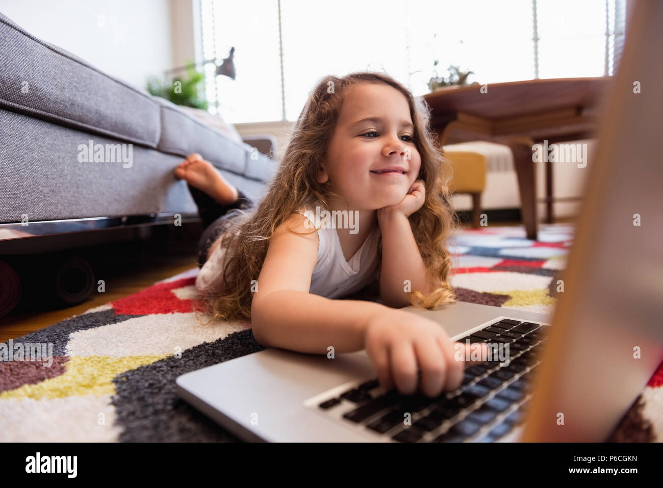 Girl lying on carpet and using laptop in living room Stock Photo - Alamy