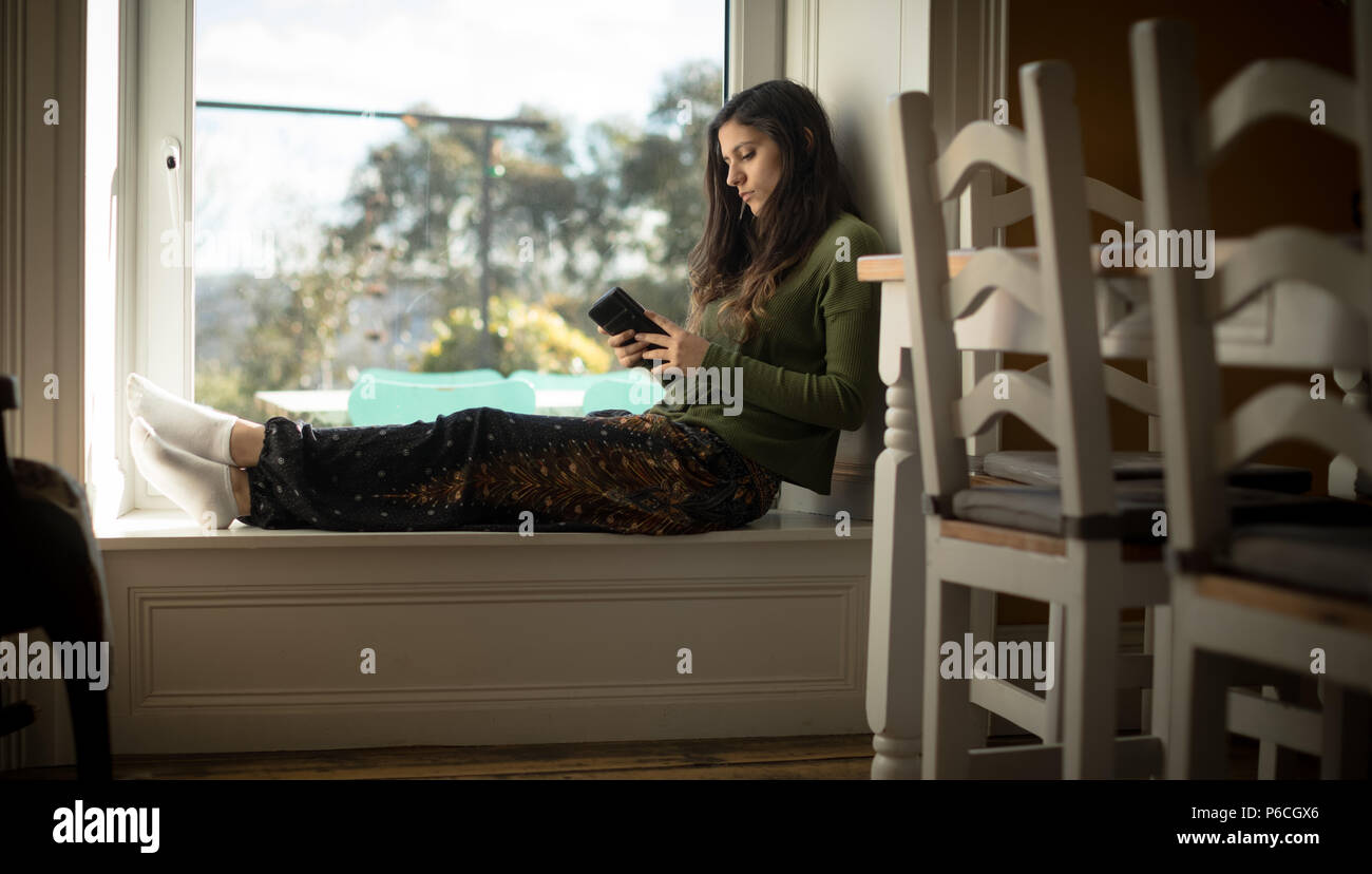 Woman using mobile phone at home Stock Photo