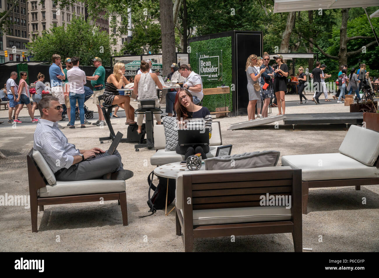 Workers in Madison Square Park in New York enjoy being outdoors at the L.L. Bean Outdoors' 'Be an Outsider at Work' pop-up co-working space on Thursday June 21, 2018. Promoting an outdoor lifestyle and reacting to research that shows workers between the ages of 22-65 spend 95 percent of their time outdoors the outdoor goods retailer created their portable pop-up office complete with a complement of comfortable office furniture and wi-fi. The busy branding event attracted many people for meetings and just to work on their laptops and was lucky enough not to be on a day where New York's oppressi Stock Photo