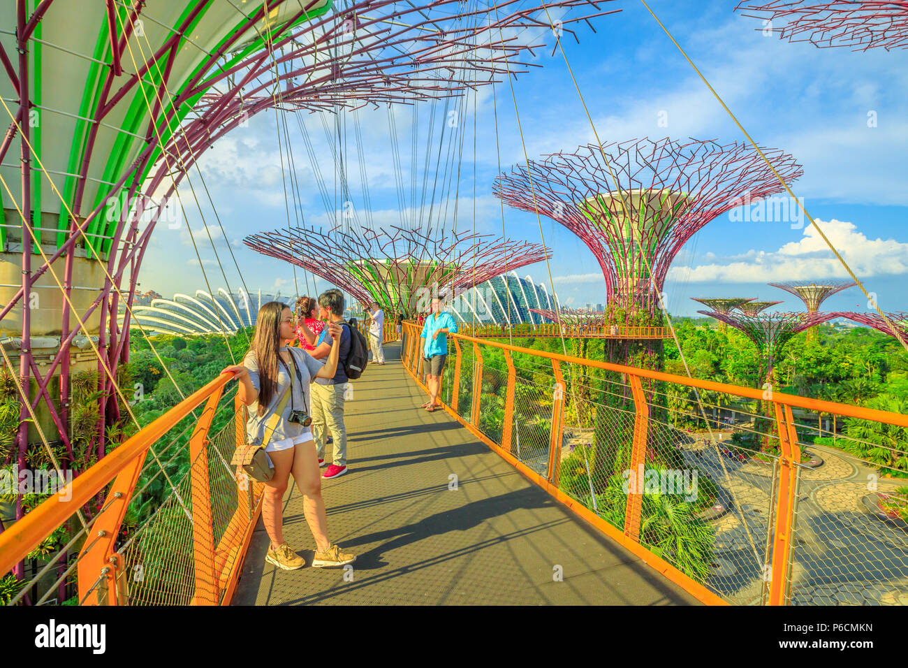 Singapore - April 29, 2018: asian tourist takes selfie with smart phone while walking on skybridge or OCBC Skyway of Supertree Grove in Gardens by the Bay, Marina Bay in Singapore. Stock Photo