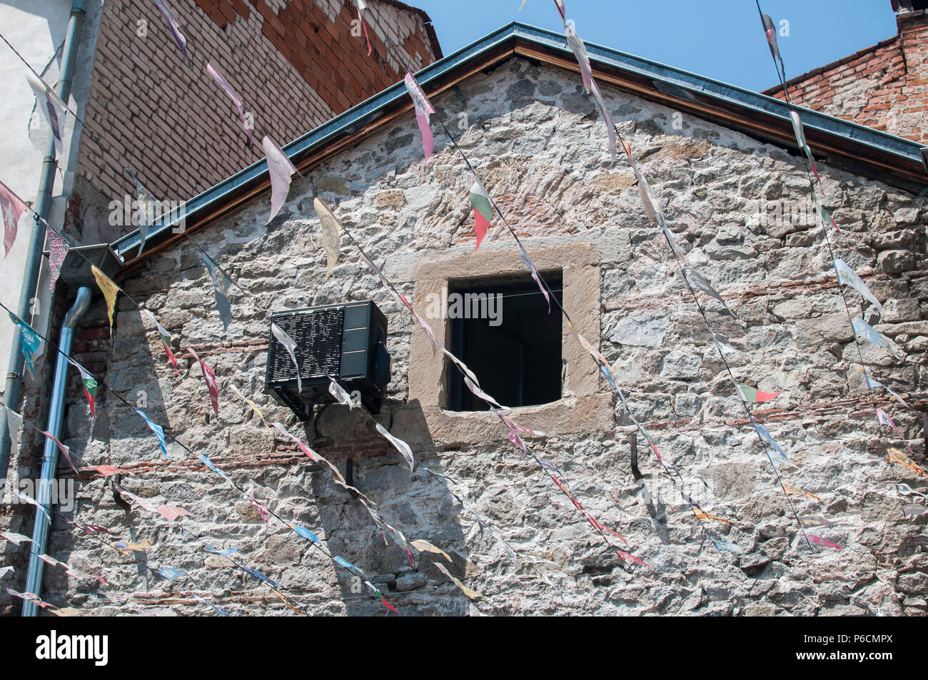 Old stone house facade wall with small window and obsolete air ...