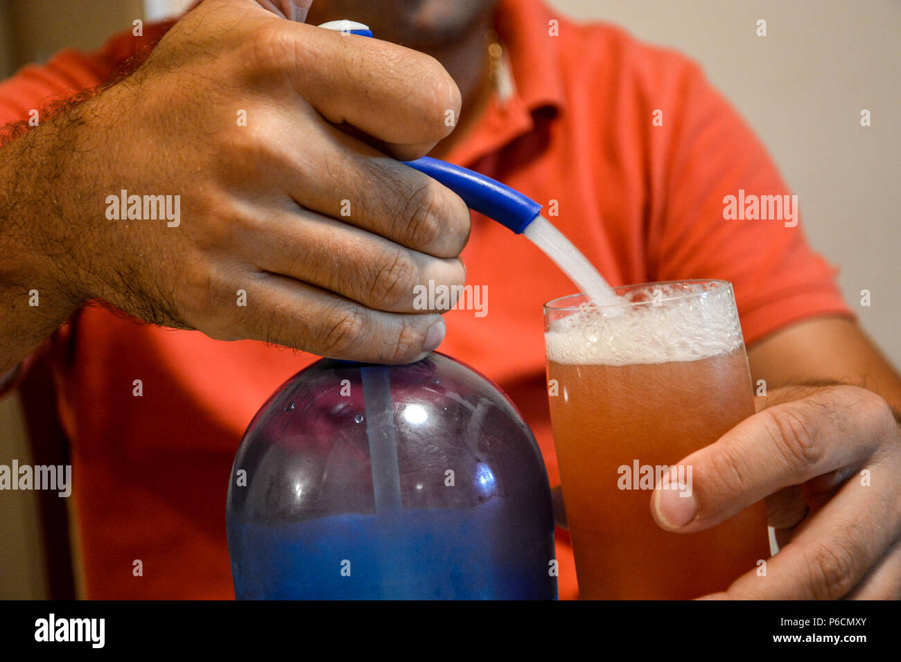Vintage water siphon pouring water over a almost full glass of red wine