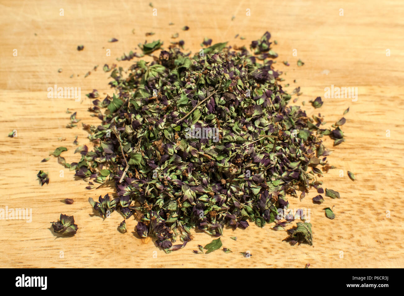 Pile of crushed dried oregano to spice up dishes closeup on wooden board background Stock Photo