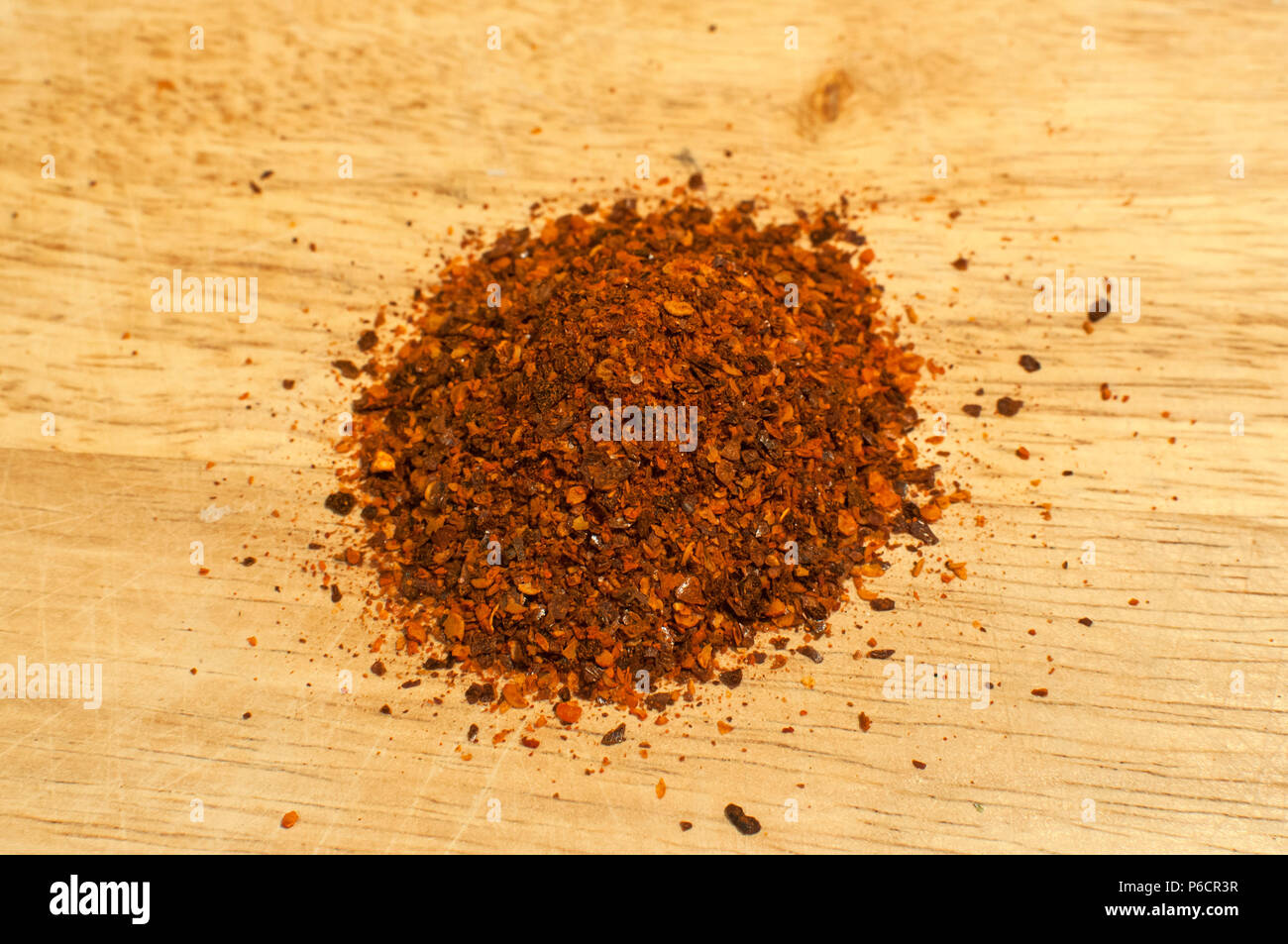 A pile of dried crushed coarse ground red hot pepper chilli flakes and