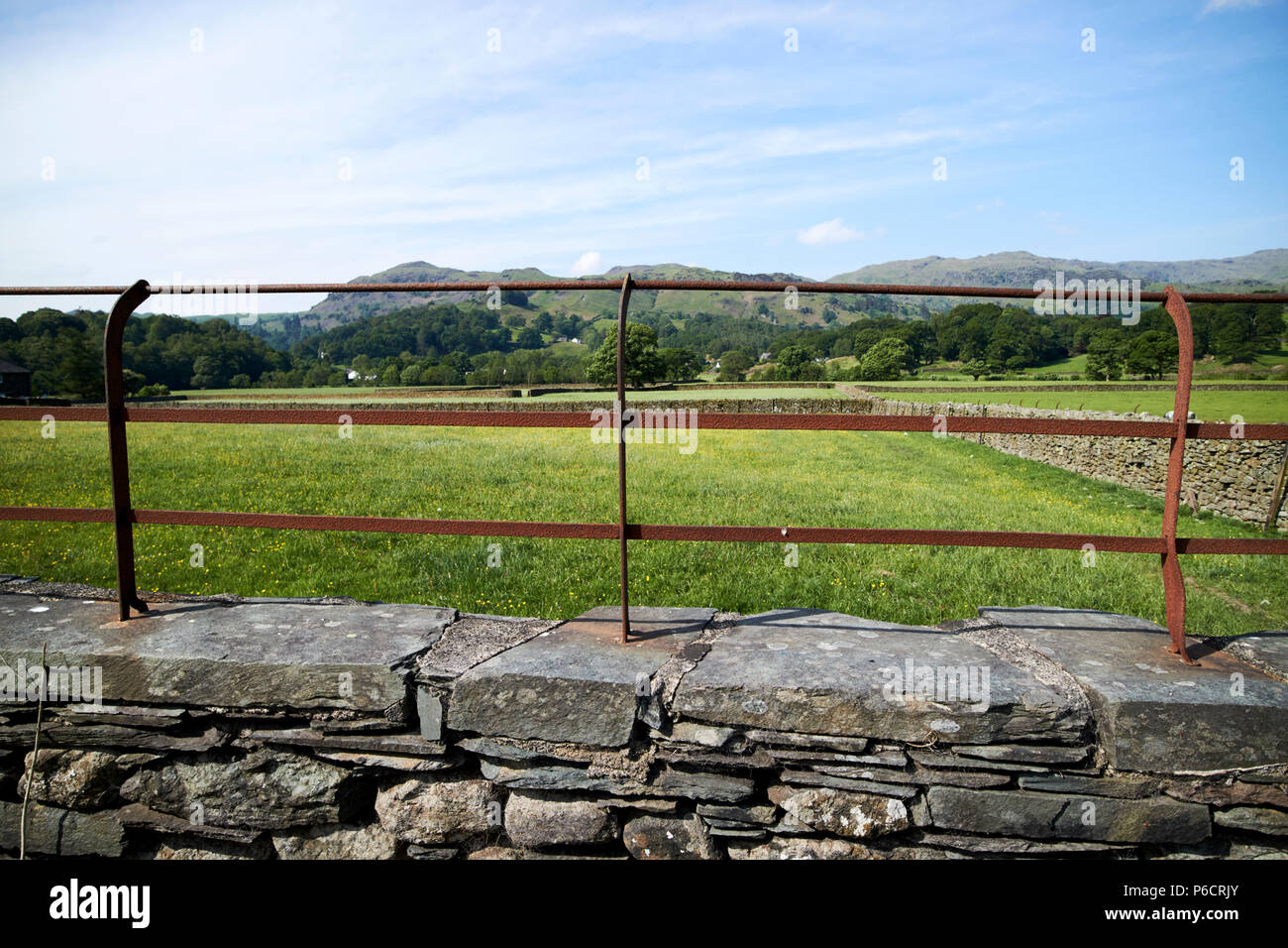 rusty metal fence on top of lakeland stone slate dry stone wall with fields  and hills near grasmere in the lake district cumbria england uk Stock Photo  - Alamy, image size:1300x956