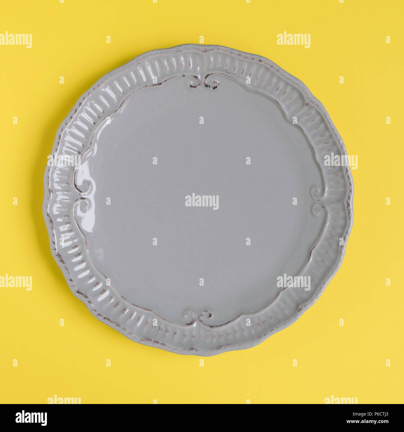 Grey rustic plate on yellow background. Square image. Top view. Stock Photo