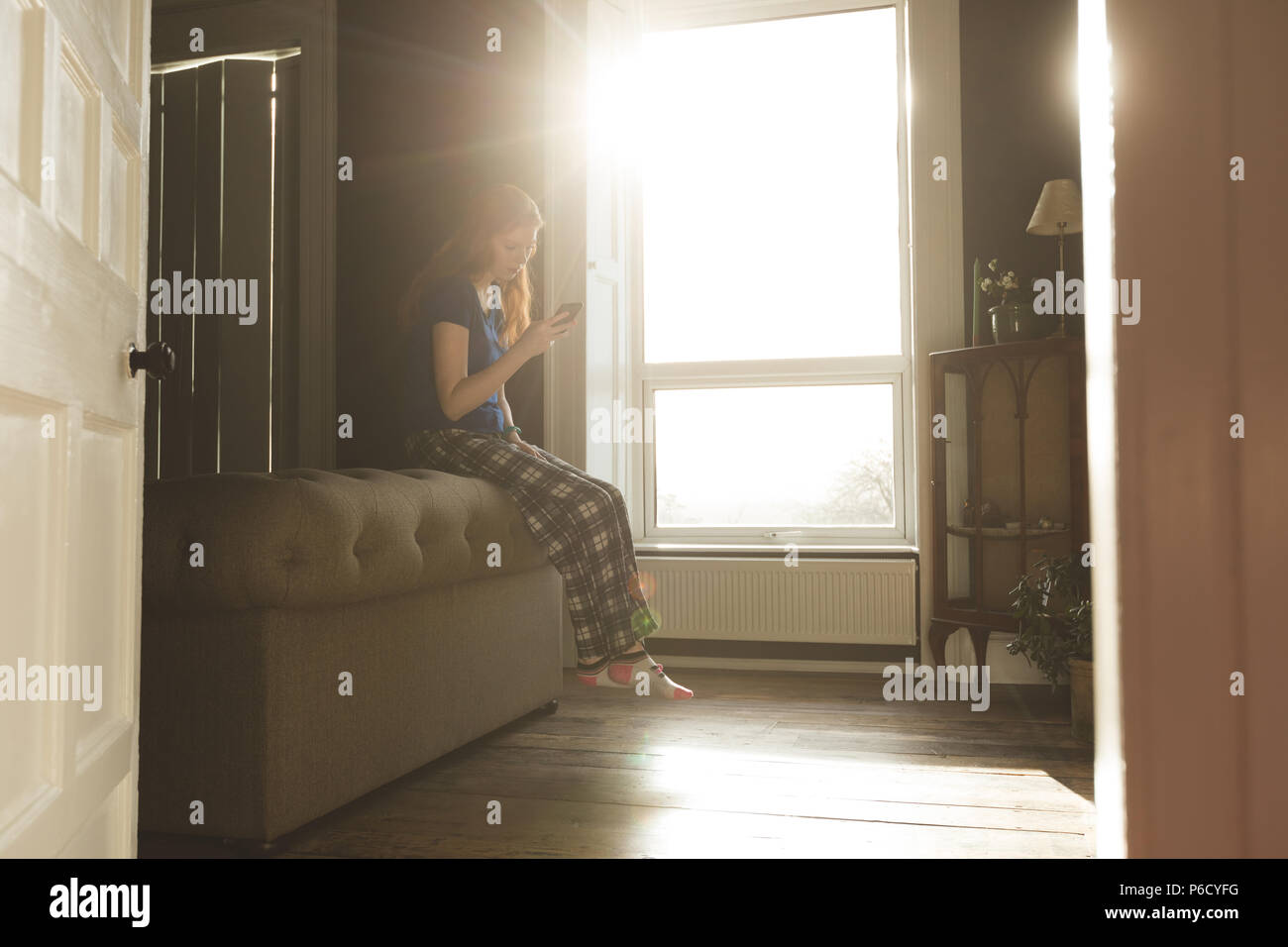 Woman using mobile phone in living room Stock Photo