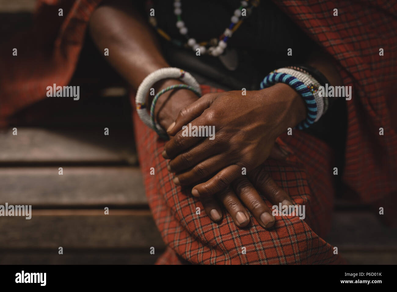 Maasai man in traditional clothing sitting on bench Stock Photo