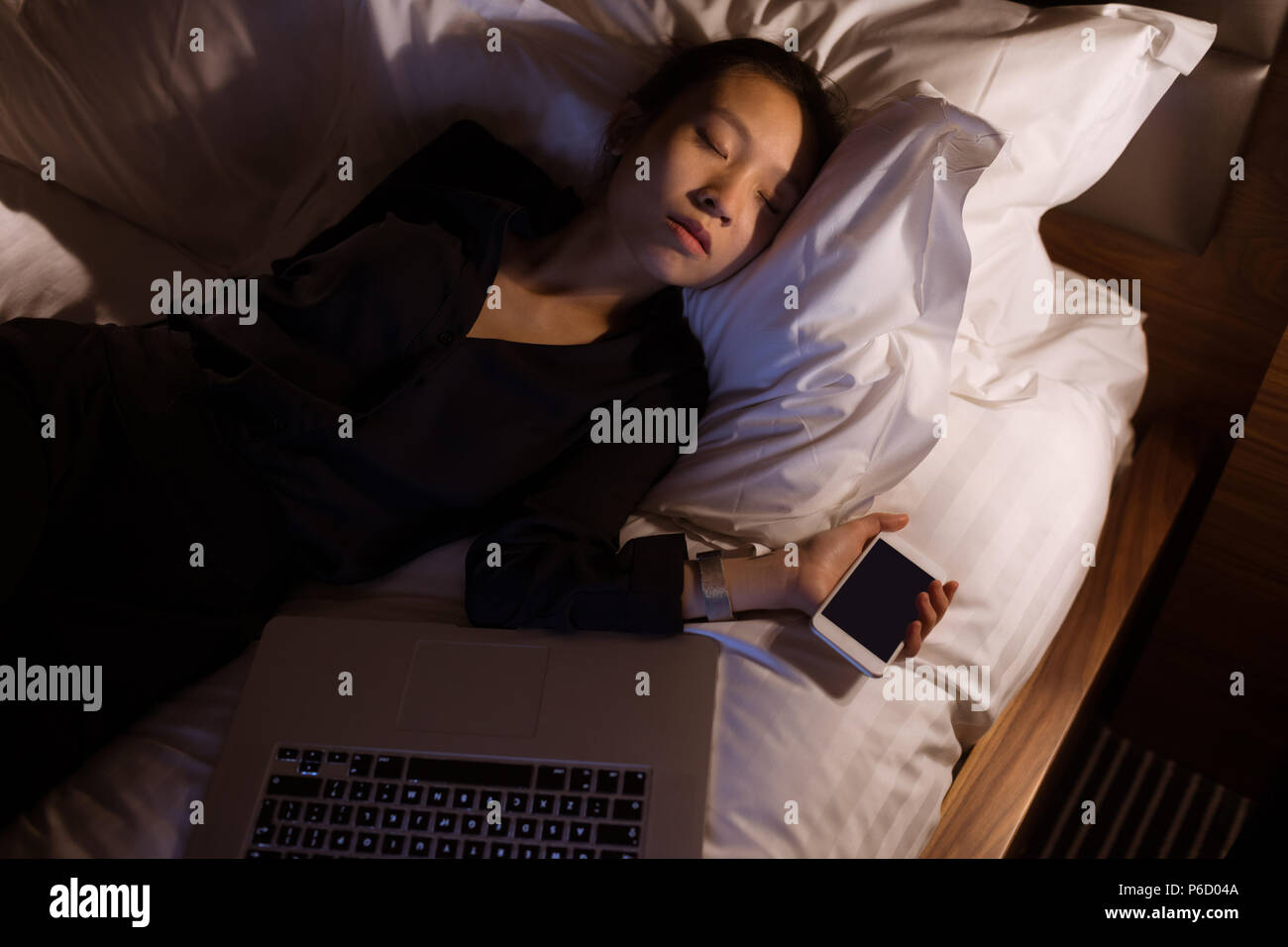 Tired woman sleeping with laptop and mobile pone on bed Stock Photo Alamy