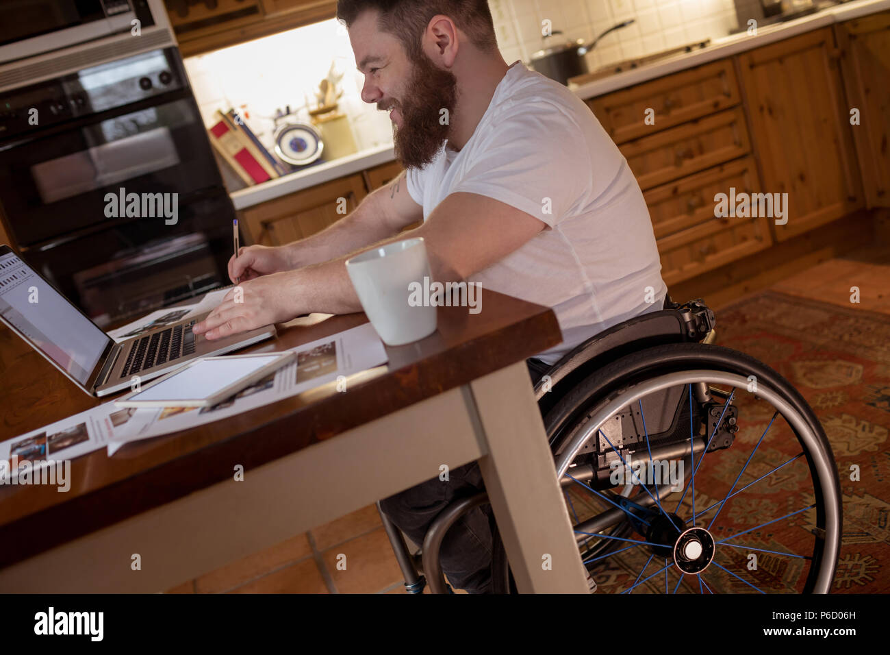 Disabled man noting while using laptop Stock Photo