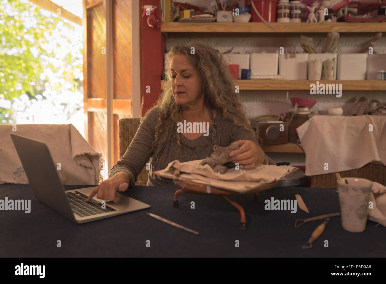 Female potter using laptop Stock Photo