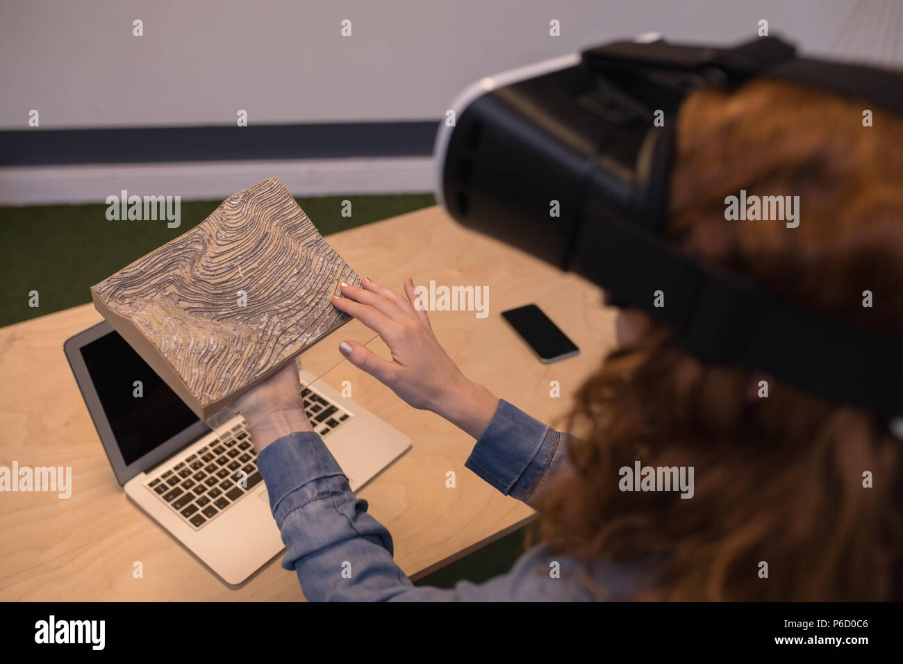 Woman touching wooden slab while using virtual reality headset Stock Photo