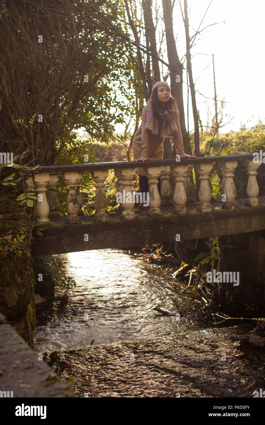 Thoughtful woman leaning on footbridge Stock Photo