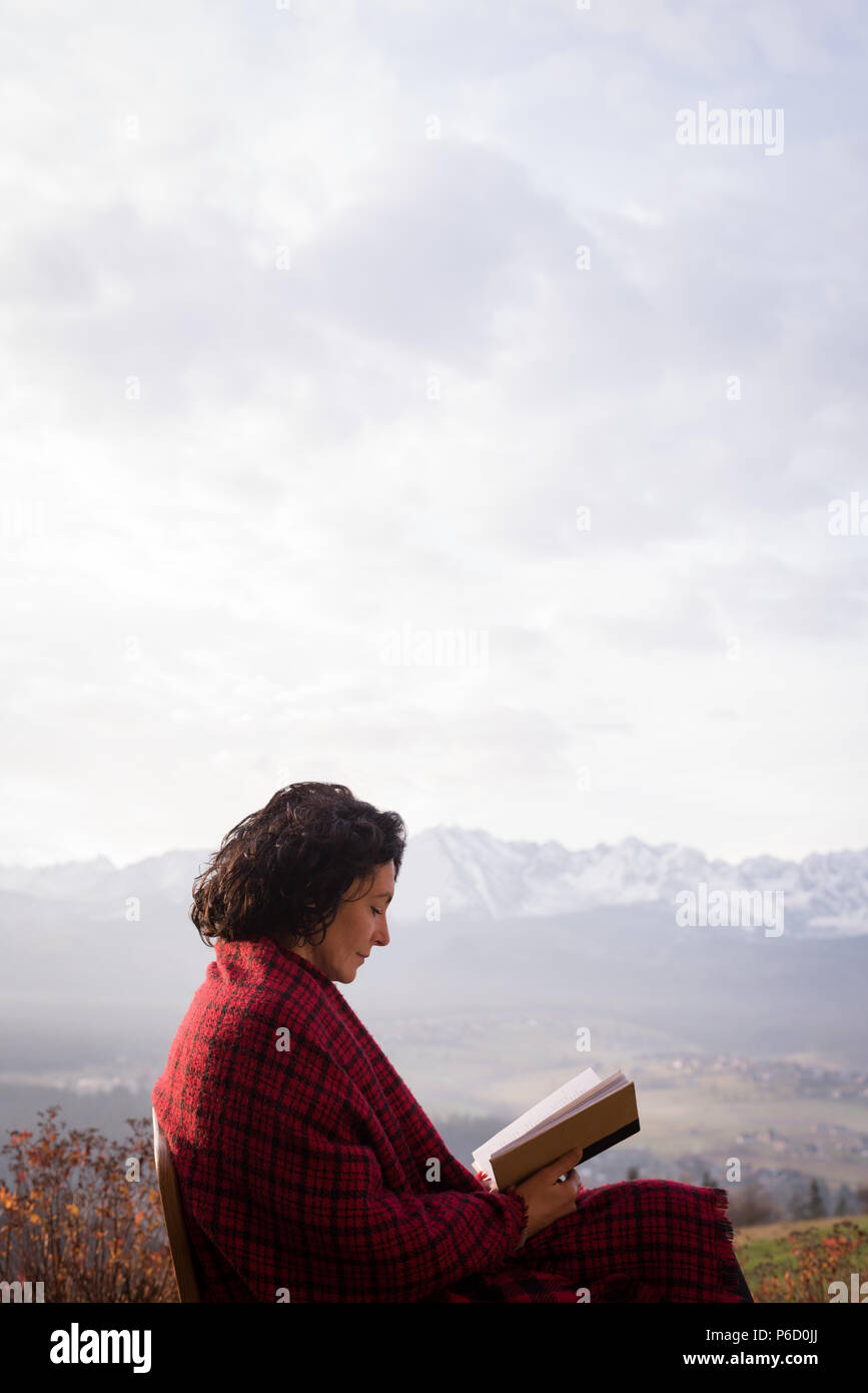 Beautiful woman wrapped in blanket reading book Stock Photo Alamy