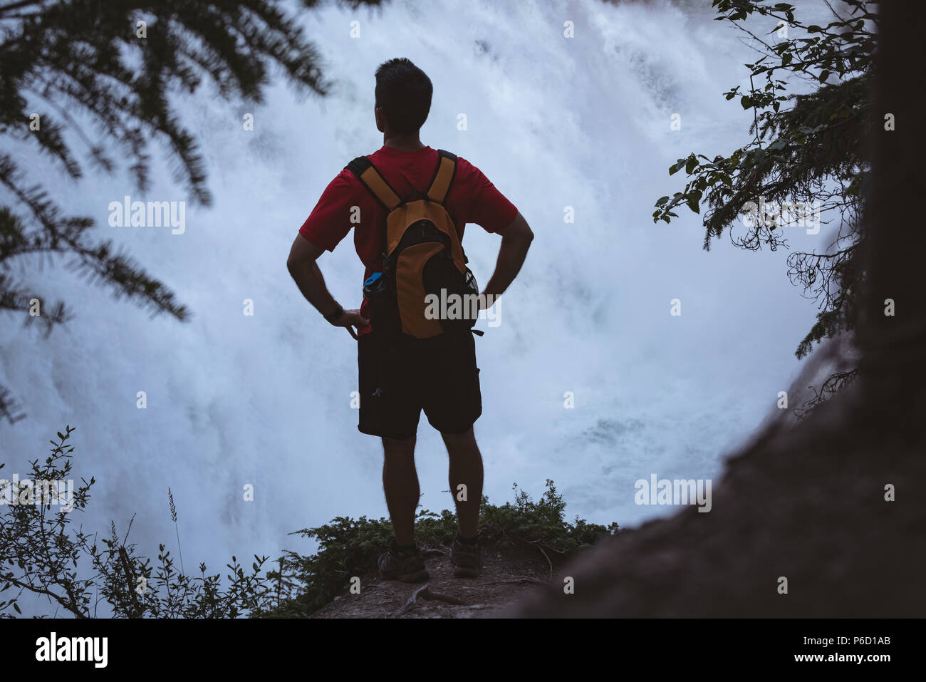 Man standing with hands on hip near waterfall Stock Photo