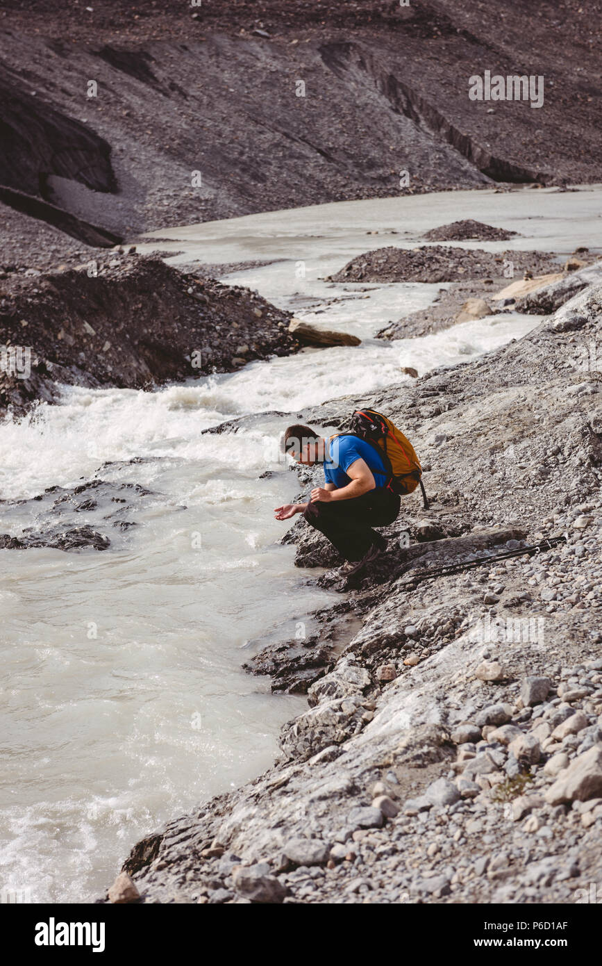 Male hiker washing his hands in river Stock Photo
