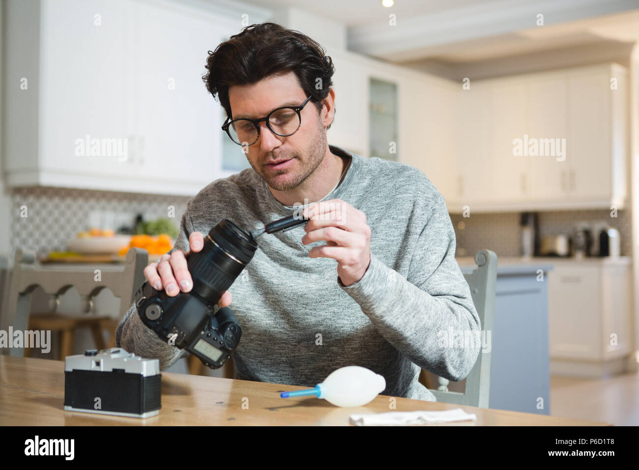 Man cleaning lens of digital camera at home Stock Photo