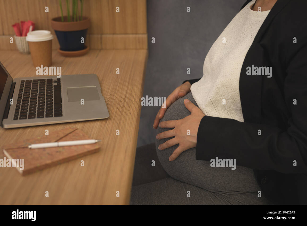 Pregnant businesswoman touching her belly at desk Stock Photo Alamy