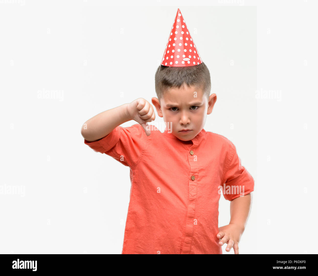 Dark haired little child wearing birthday cap with angry face, negative